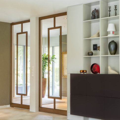 Dubbele bronzen stalen deuren met glas als elegante scheiding tussen hal en woonkamer.